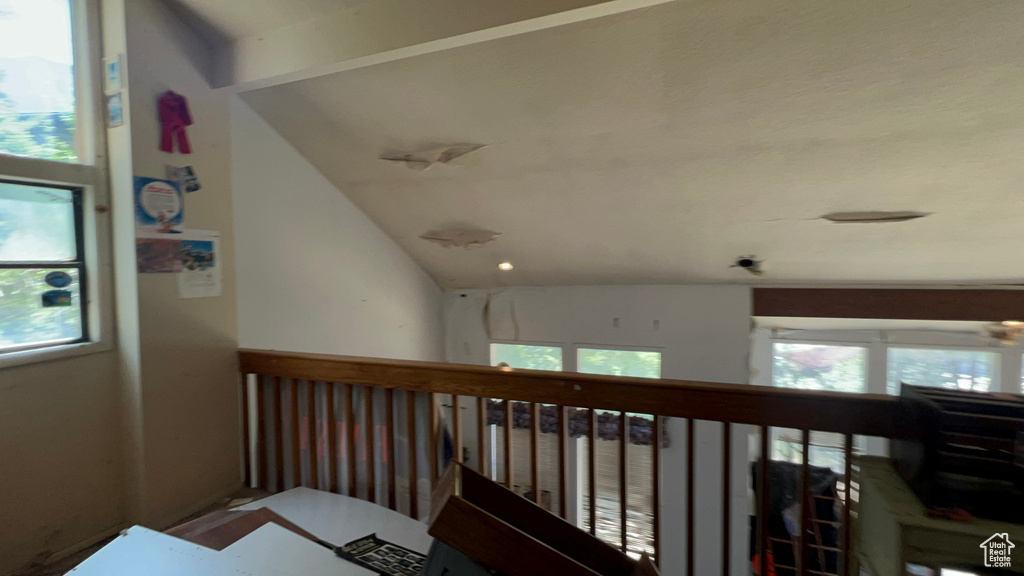 Corridor featuring plenty of natural light, an upstairs landing, and lofted ceiling