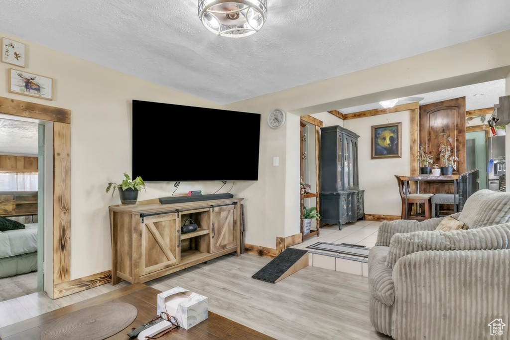 Living area with light wood finished floors, a textured ceiling, and lofted ceiling