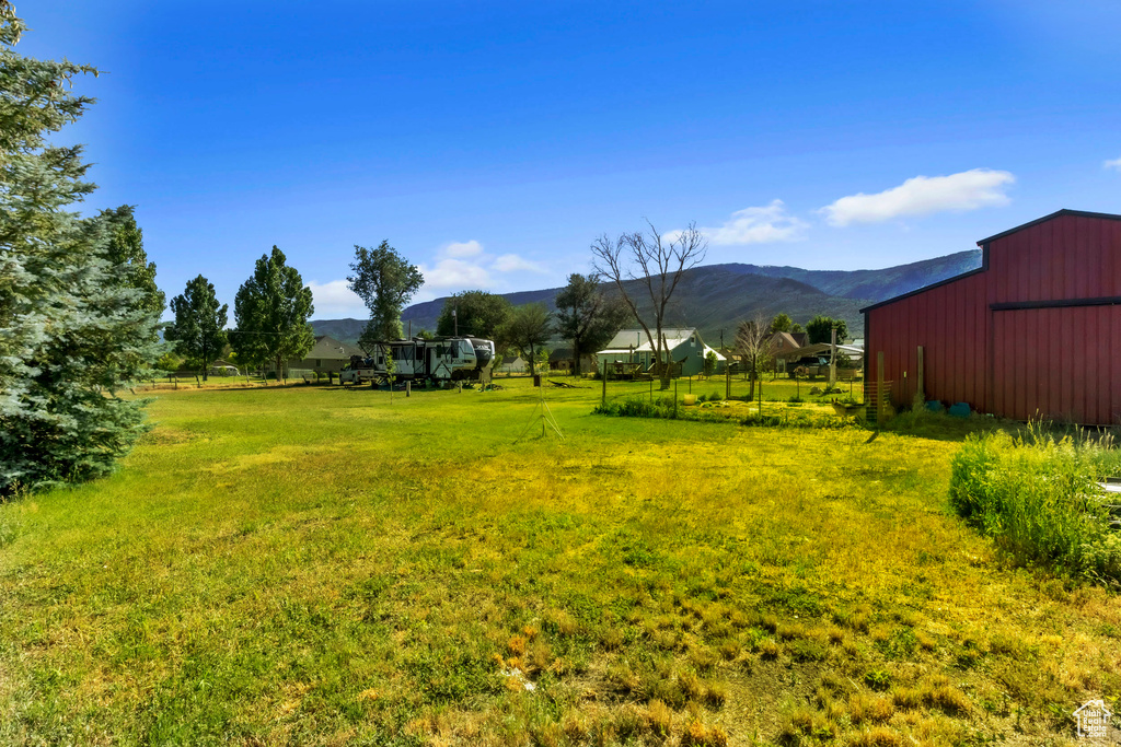 View of green lawn featuring an outdoor structure, a mountain view, and a pole building