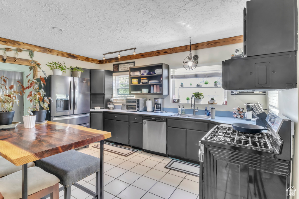 Kitchen featuring appliances with stainless steel finishes, open shelves, rail lighting, light tile patterned floors, and a textured ceiling