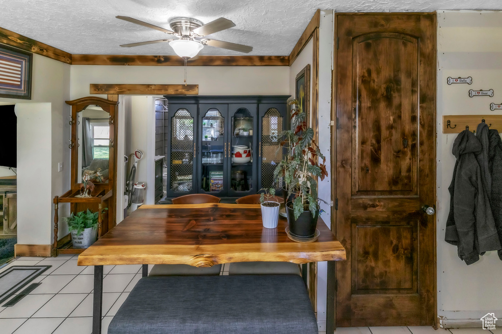 Dining area featuring a ceiling fan, a textured ceiling, and light tile patterned floors