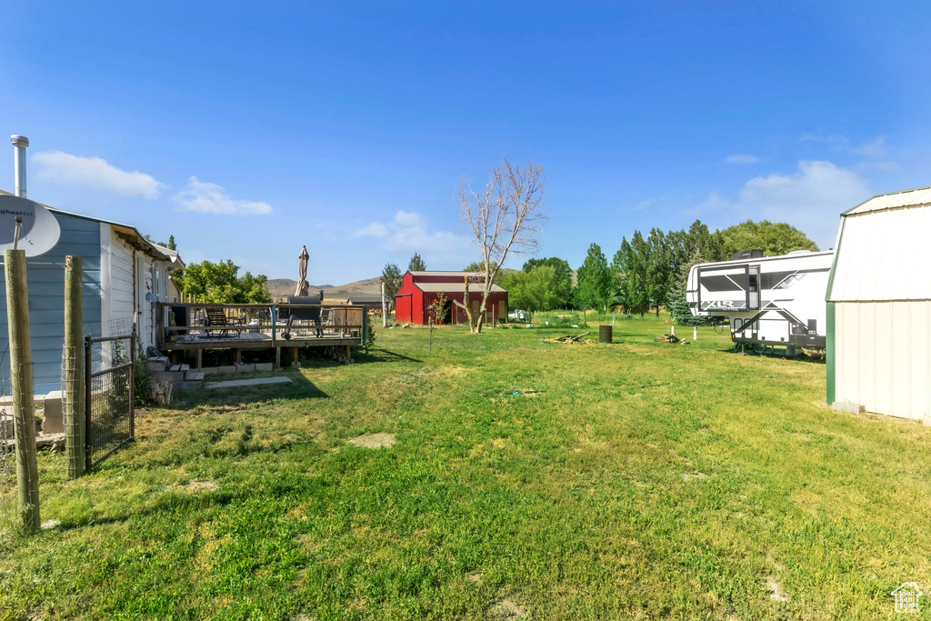 View of grassy yard with an outdoor structure and a deck