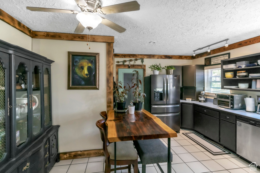 Kitchen featuring stainless steel appliances, light tile patterned floors, track lighting, a textured ceiling, and a ceiling fan