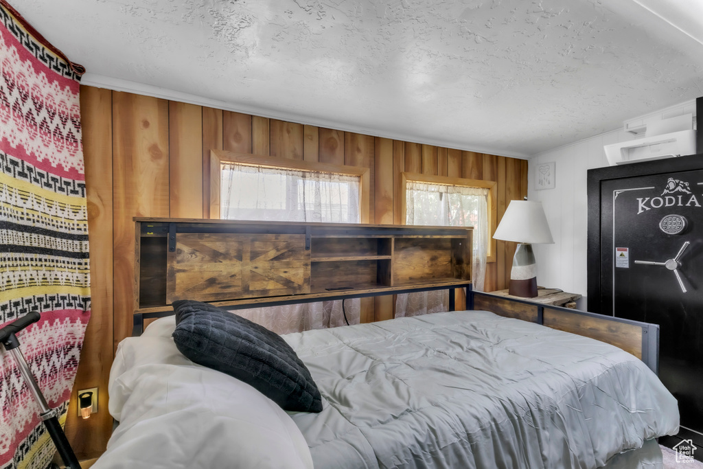 Bedroom featuring a textured ceiling and wood walls
