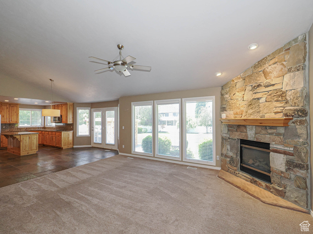 Unfurnished living room with vaulted ceiling, a stone fireplace, ceiling fan, dark carpet, and recessed lighting
