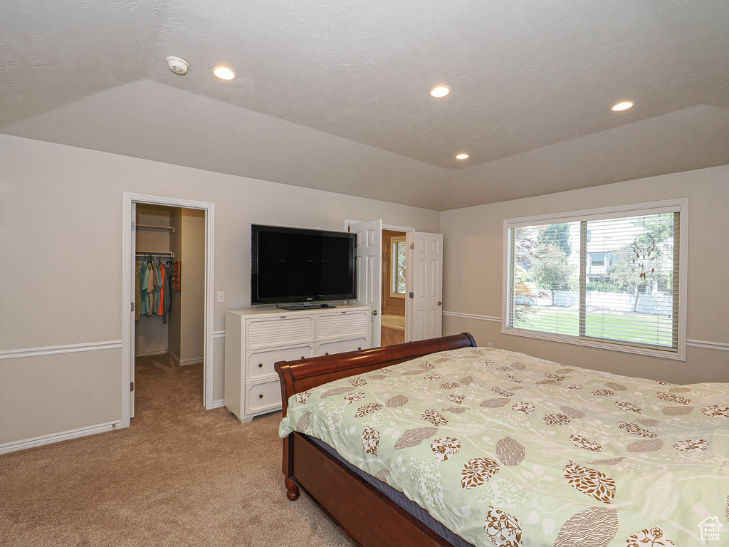 Bedroom with a walk in closet, light carpet, recessed lighting, and a closet