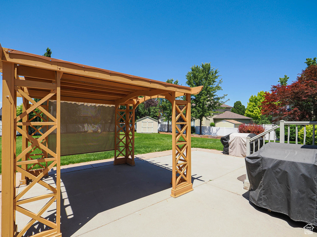 View of patio with a shed and a grill