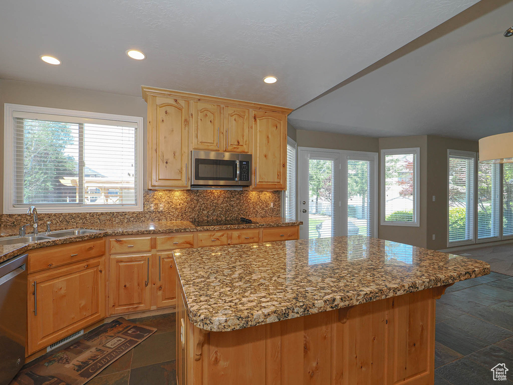 Kitchen with stainless steel appliances, stone tile flooring, decorative backsplash, recessed lighting, and stone countertops