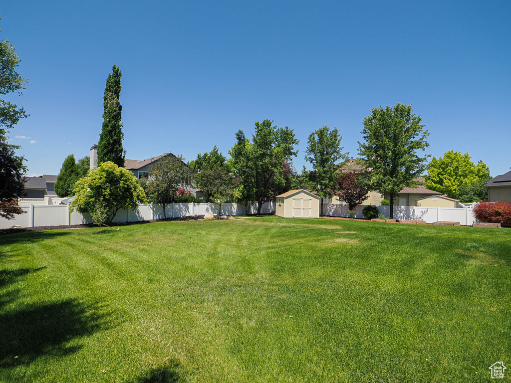 Fenced backyard featuring a storage unit