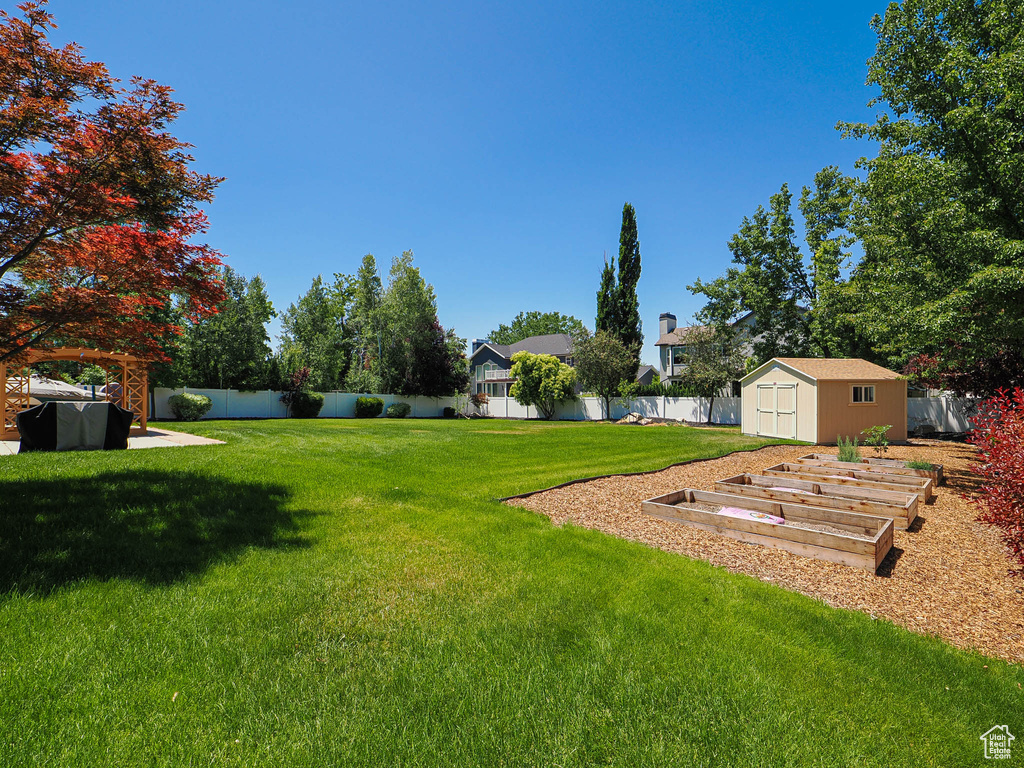 Fenced backyard featuring a storage shed and a garden