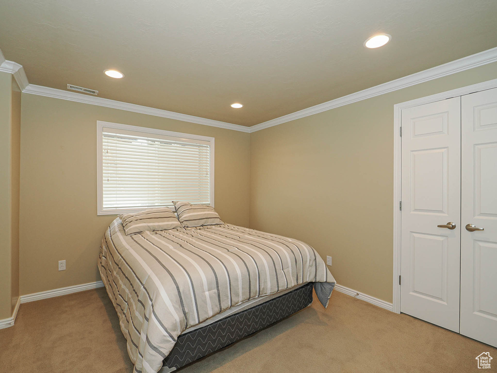 Bedroom with light carpet, crown molding, and recessed lighting