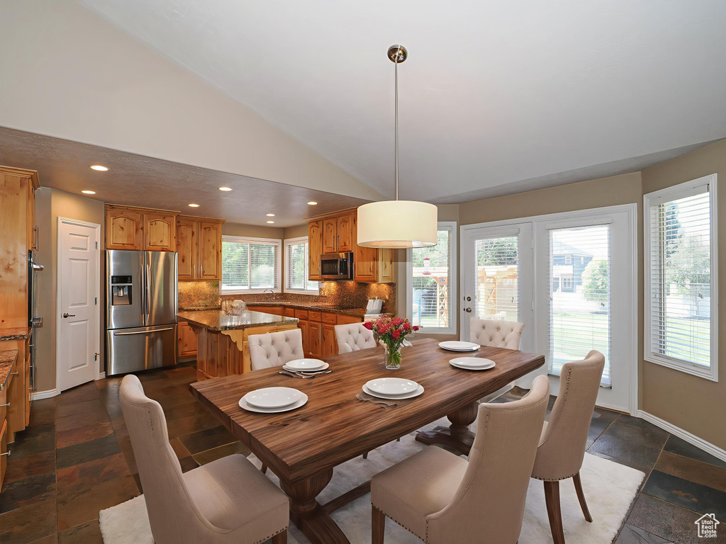 Dining space featuring recessed lighting, vaulted ceiling, and stone tile floors