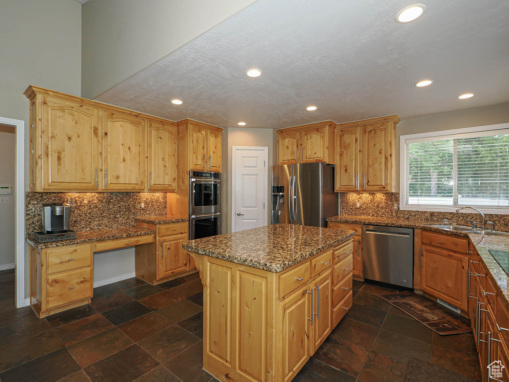 Kitchen with appliances with stainless steel finishes, dark stone countertops, recessed lighting, tasteful backsplash, and a kitchen island