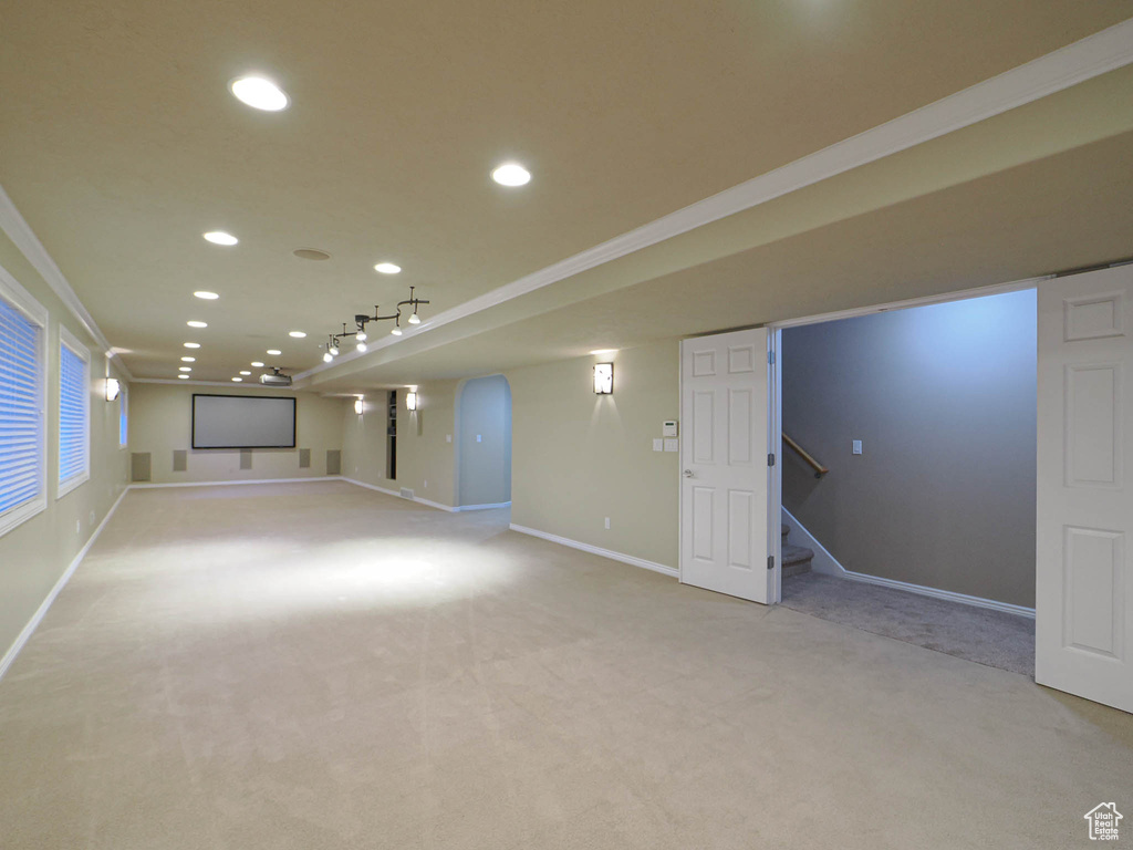Finished basement featuring ornamental molding, light carpet, recessed lighting, and stairs