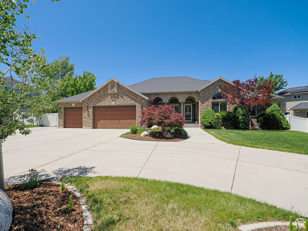 View of front facade featuring a garage, concrete driveway, brick siding, and roof with shingles