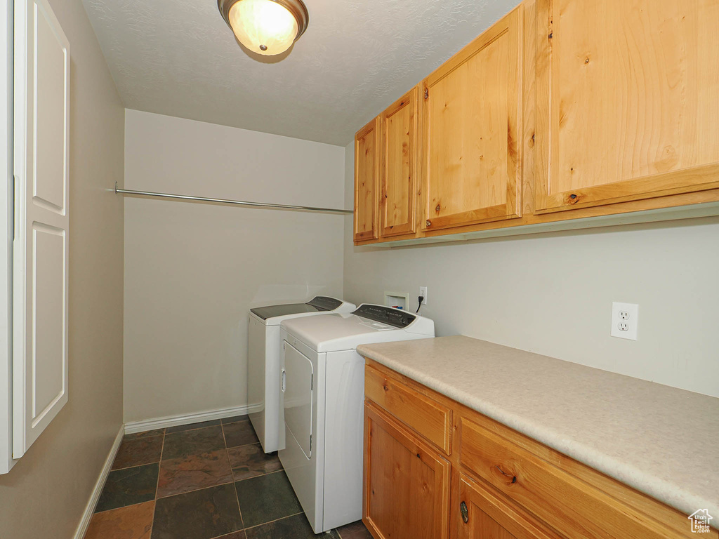 Laundry area with cabinet space, washer and dryer, and dark stone finish flooring