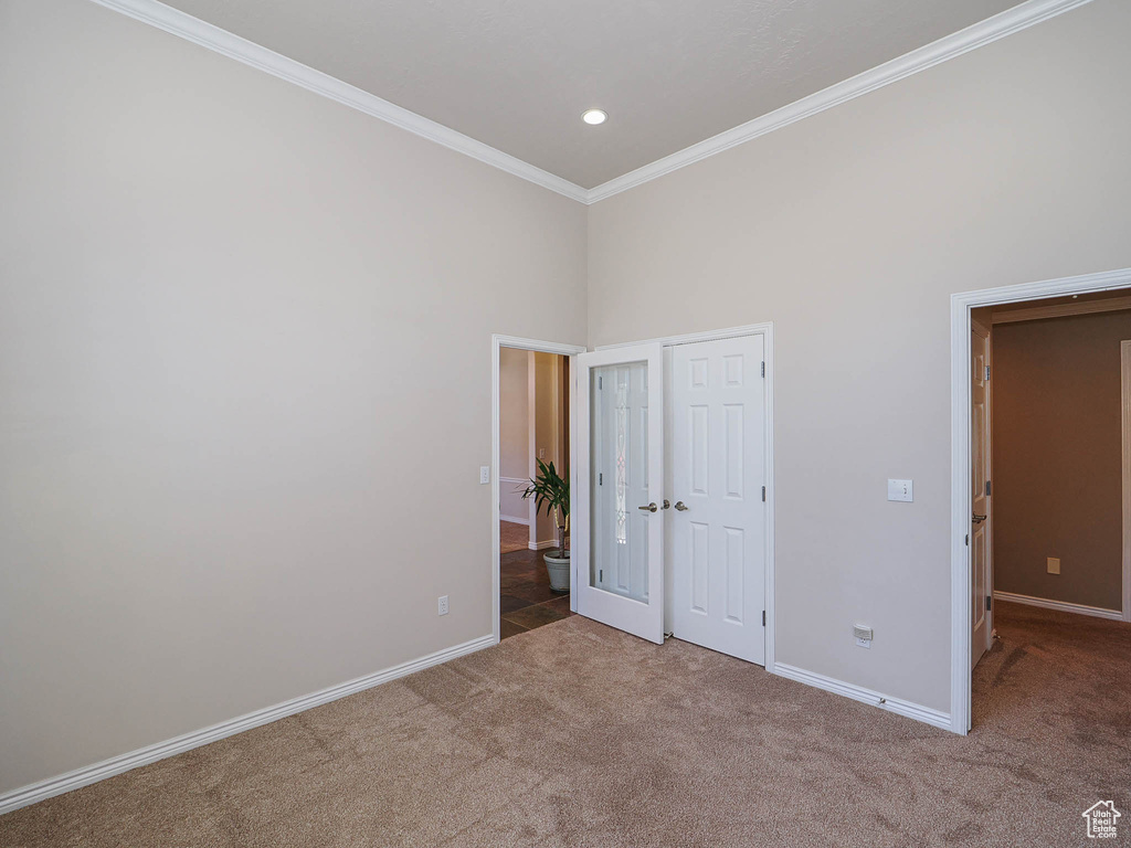 Unfurnished bedroom featuring carpet flooring, crown molding, recessed lighting, and a towering ceiling