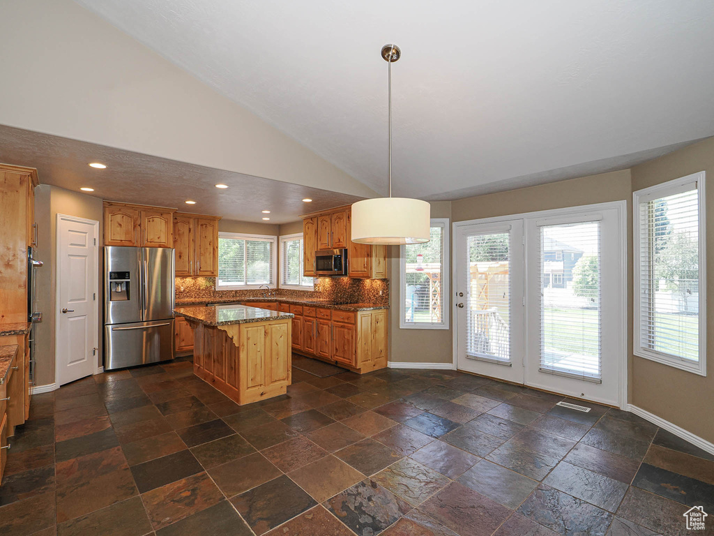 Kitchen featuring appliances with stainless steel finishes, tasteful backsplash, recessed lighting, a center island, and dark stone countertops