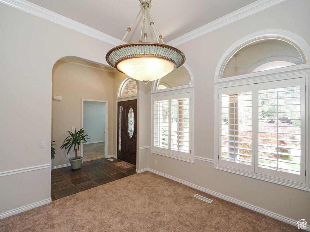 Entryway with stone tile floors, carpet floors, and crown molding