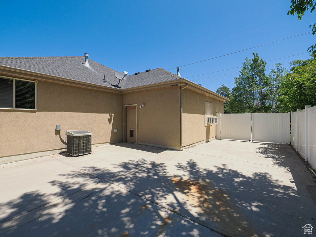 Back of property with stucco siding, a patio area, a gate, and roof with shingles