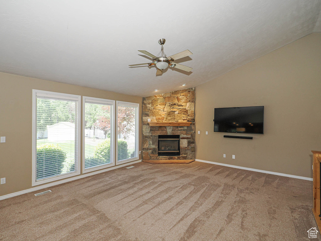 Unfurnished living room featuring vaulted ceiling, ceiling fan, carpet flooring, and a fireplace