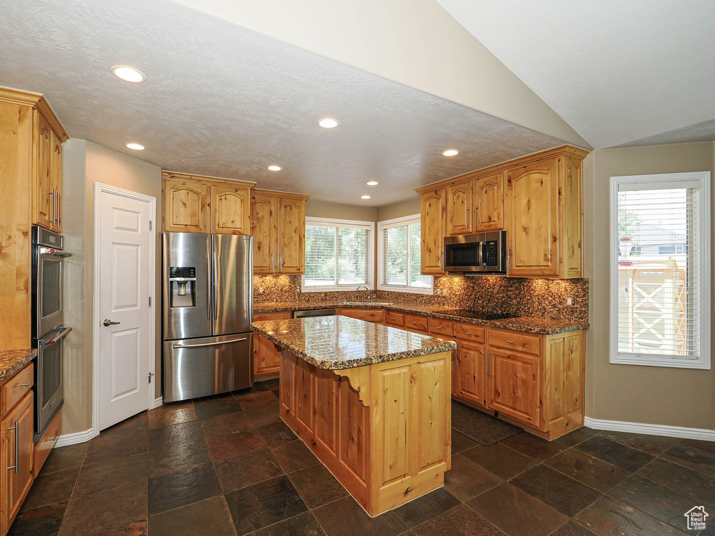 Kitchen featuring appliances with stainless steel finishes, recessed lighting, a kitchen island, stone countertops, and decorative backsplash