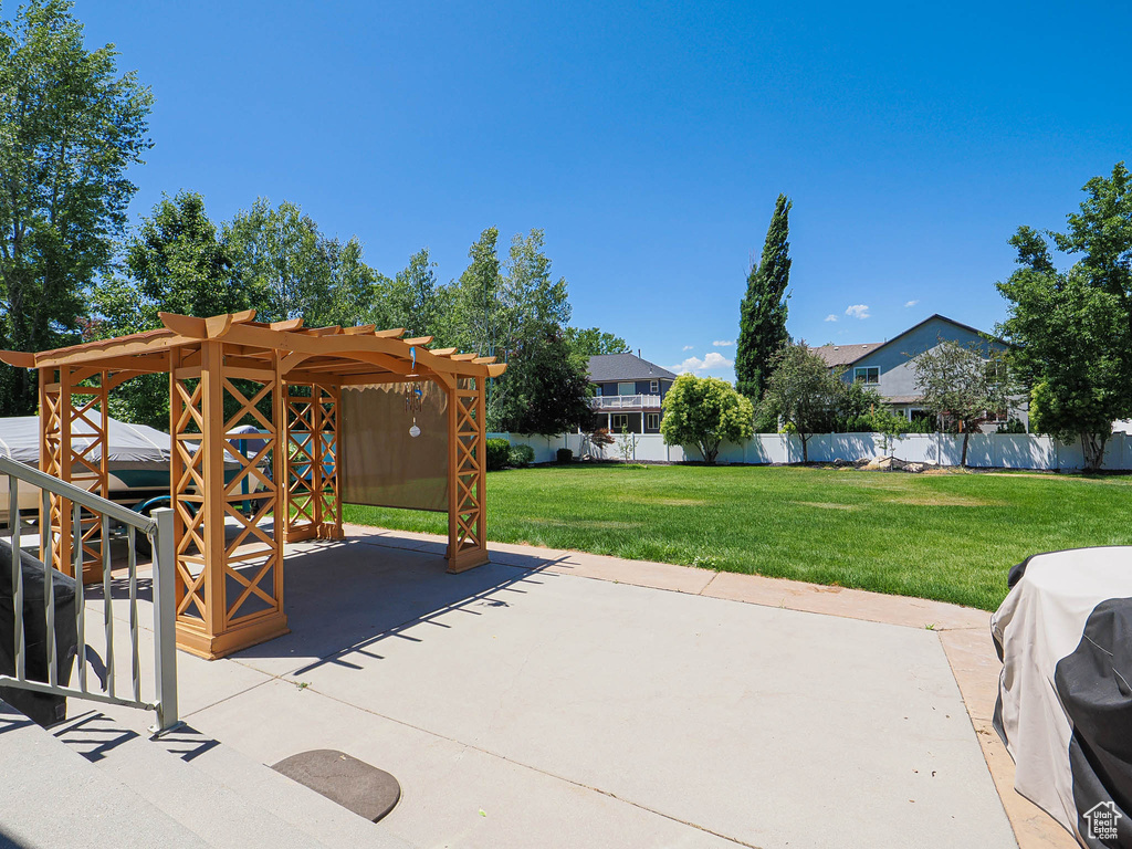 View of patio with area for grilling and a pergola