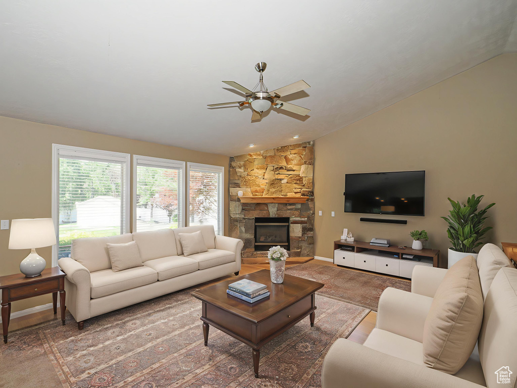 Living room with vaulted ceiling, ceiling fan, and a fireplace