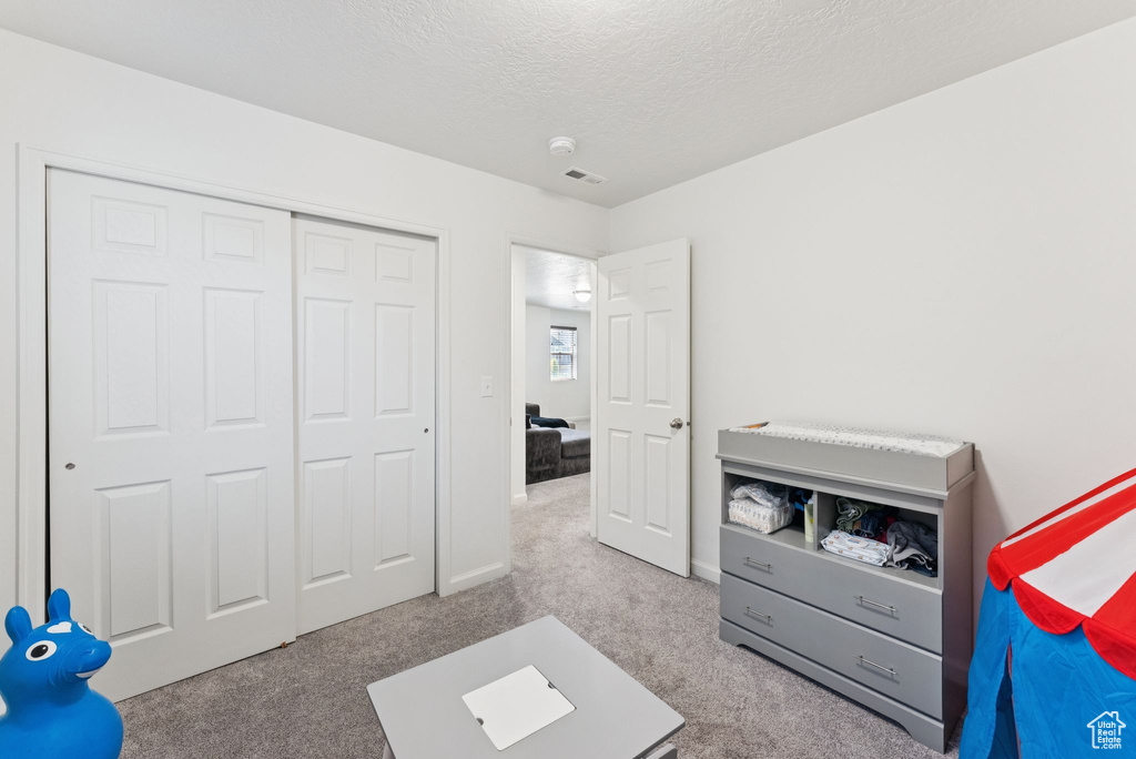 Bedroom with carpet flooring, a textured ceiling, and a closet