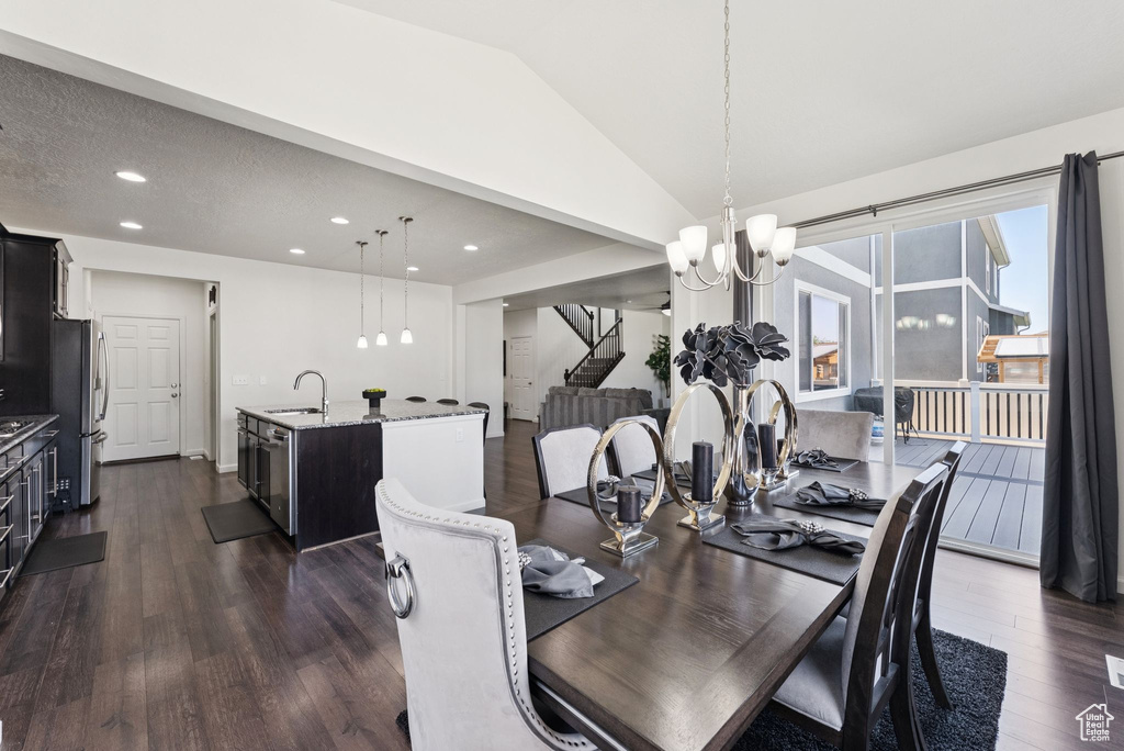 Dining room featuring stairs, dark wood-style floors, lofted ceiling, recessed lighting, and a chandelier