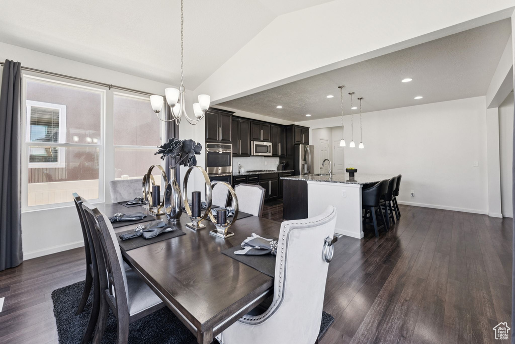 Dining area with a chandelier, lofted ceiling, dark wood-type flooring, and recessed lighting