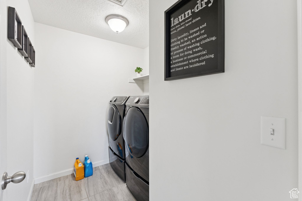 Washroom featuring washer and clothes dryer and a textured ceiling