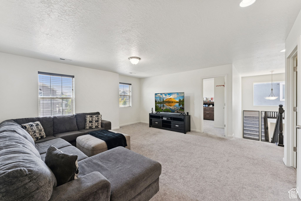 Carpeted living area featuring a textured ceiling and baseboards