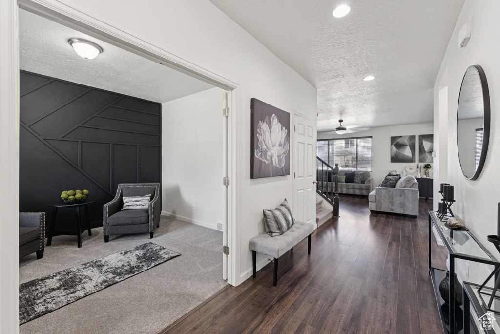 Hallway featuring a textured ceiling, dark wood finished floors, recessed lighting, and stairs