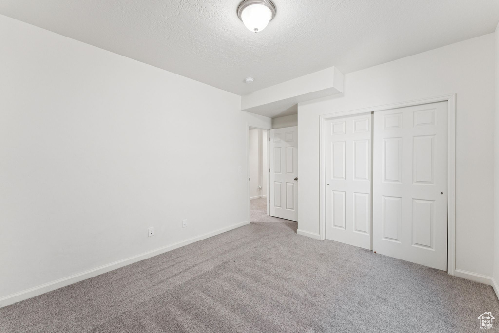 Unfurnished bedroom featuring carpet, a textured ceiling, and a closet