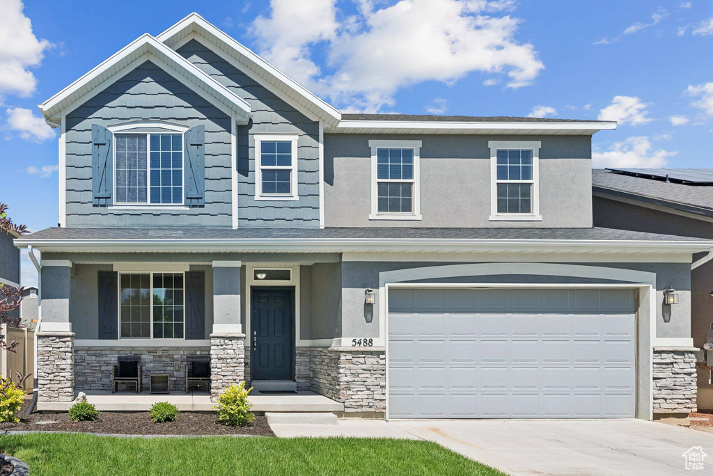 Craftsman inspired home featuring stone siding, a porch, driveway, and stucco siding