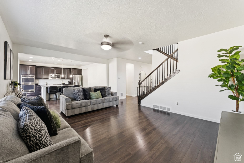 Living area featuring dark wood-style flooring, stairway, a ceiling fan, recessed lighting, and a textured ceiling