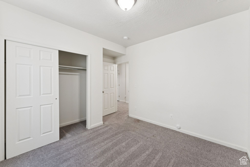 Unfurnished bedroom with carpet flooring, a closet, and a textured ceiling