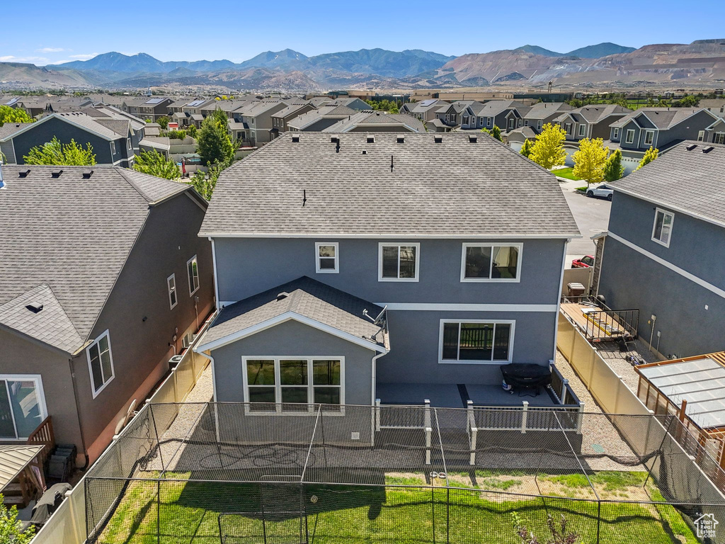 Rear view of house with stucco siding, a residential view, a mountain view, a fenced backyard, and roof with shingles
