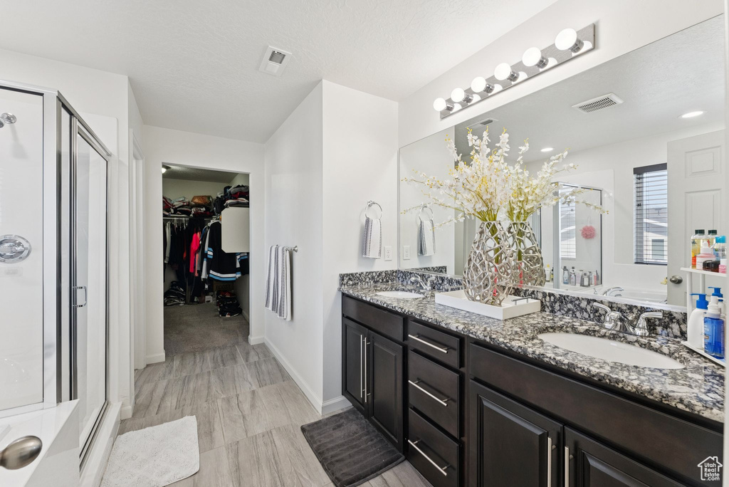 Full bath with a stall shower, double vanity, and a walk in closet
