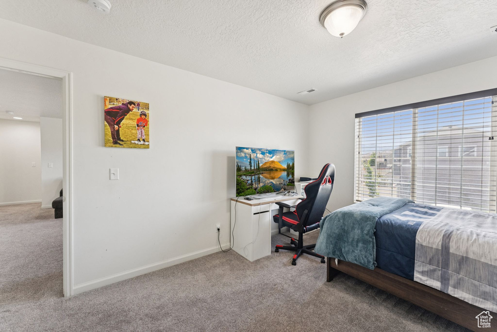 Carpeted bedroom featuring a textured ceiling and baseboards