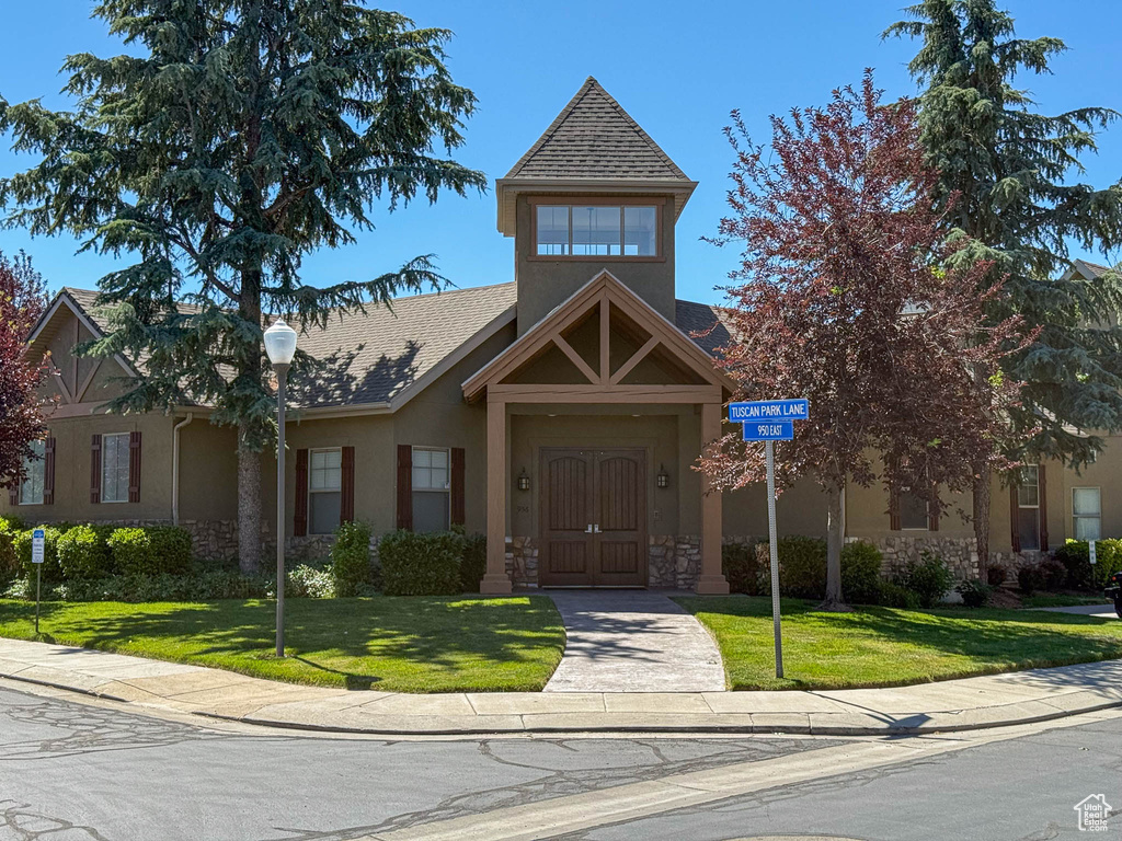 View of front of home with stucco siding, stone siding, and a front yard