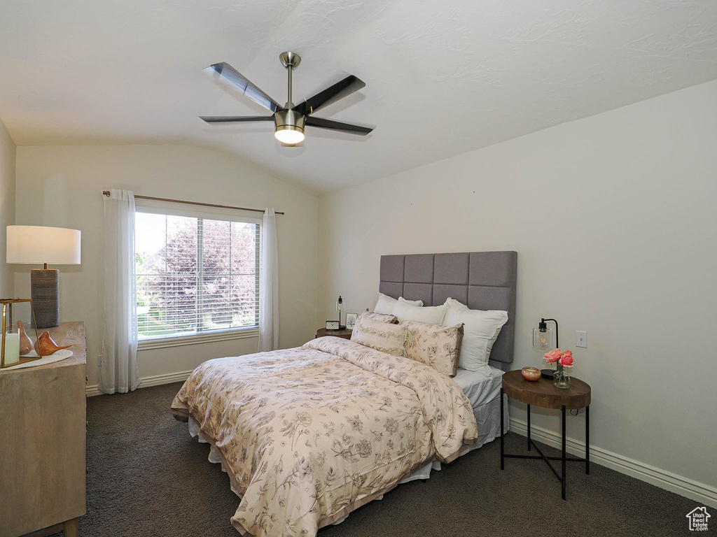 Bedroom with vaulted ceiling, dark carpet, and a ceiling fan