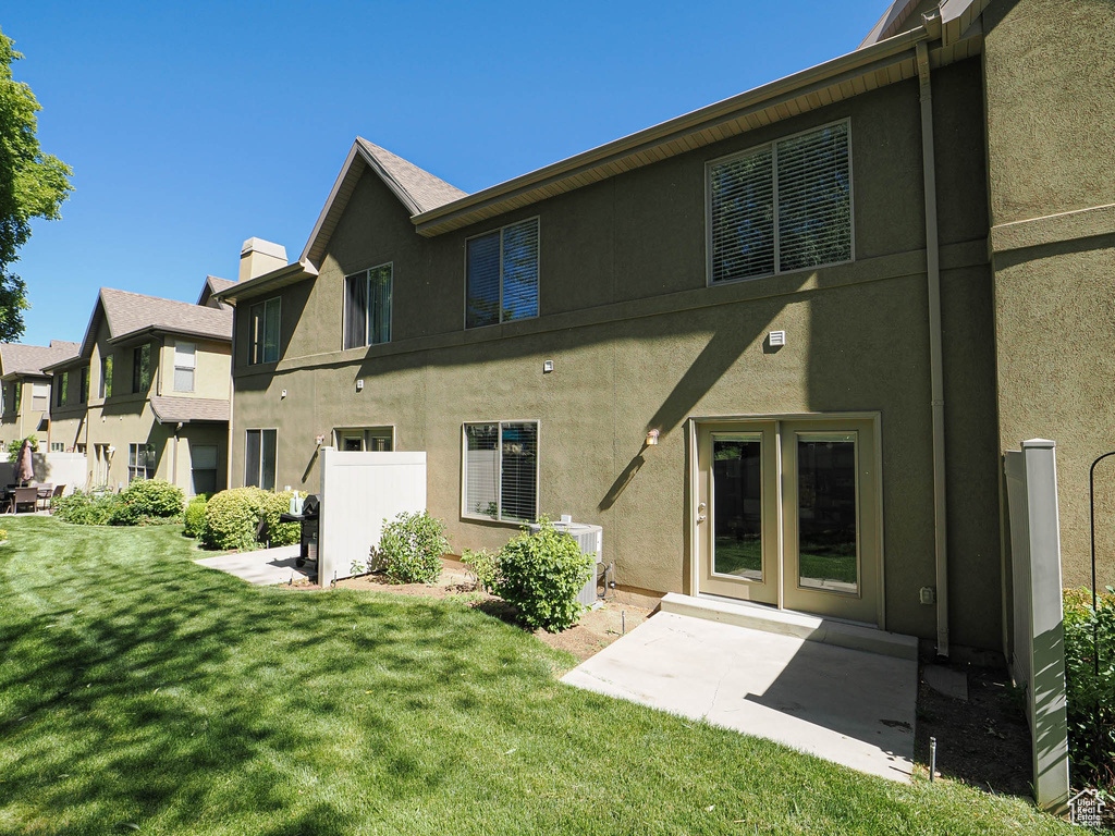 Rear view of property with stucco siding, a yard, and a chimney