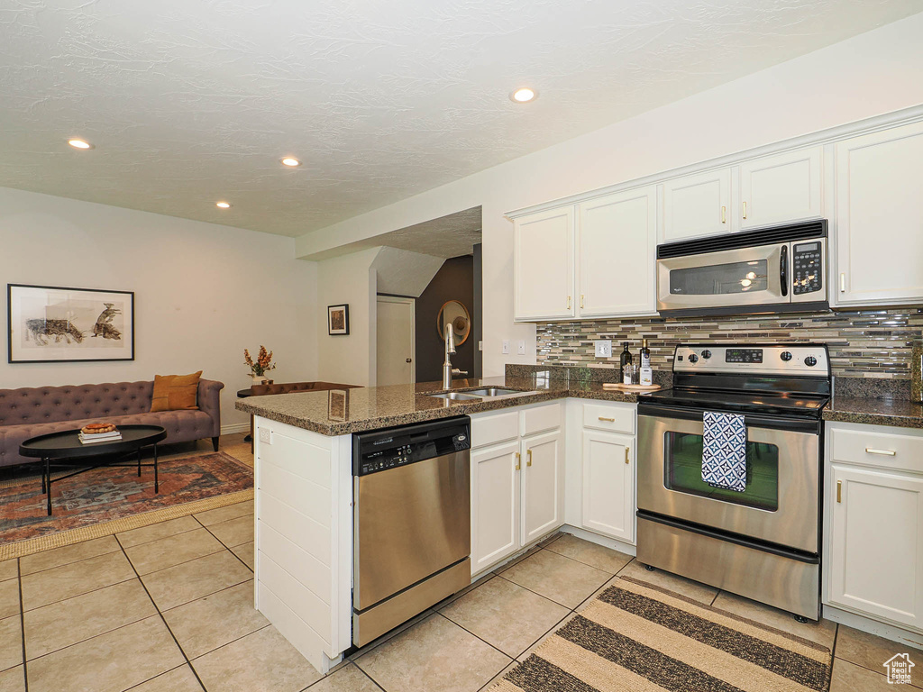 Kitchen featuring stainless steel appliances, decorative backsplash, white cabinetry, and recessed lighting