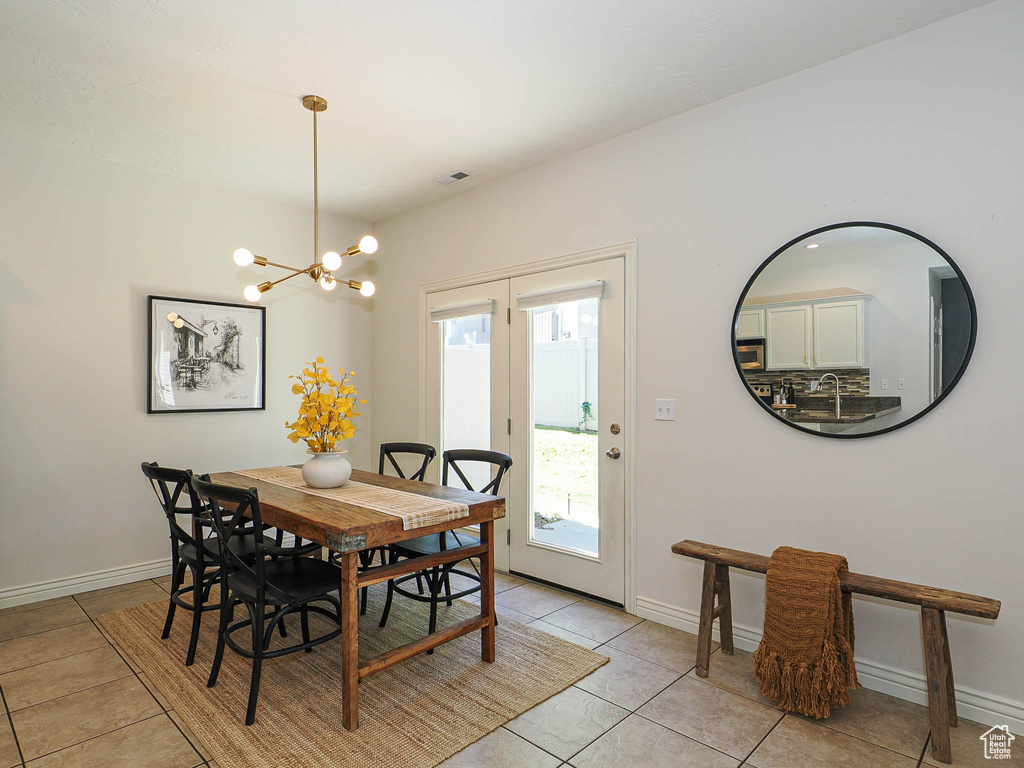 Dining area with light tile patterned floors and a chandelier