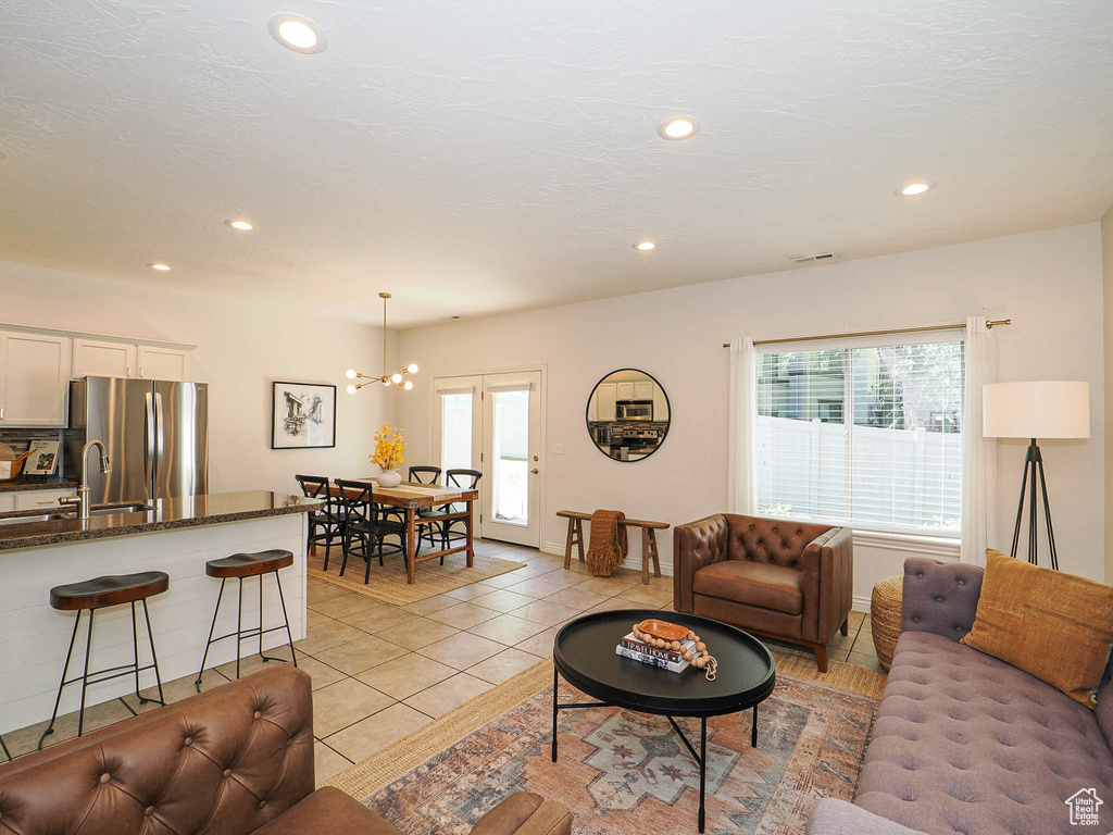 Living room with plenty of natural light, recessed lighting, light tile patterned floors, and a chandelier