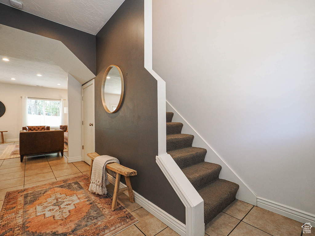 Stairway with tile patterned flooring and recessed lighting