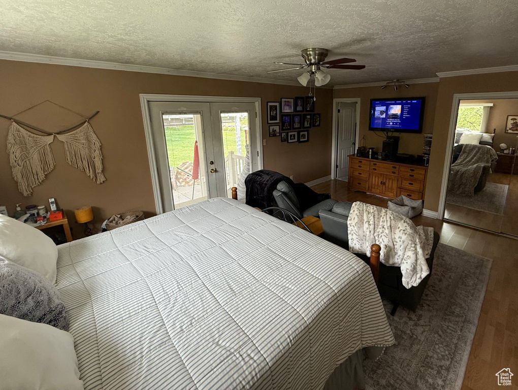 Bedroom with access to exterior, wood finished floors, french doors, a textured ceiling, and crown molding