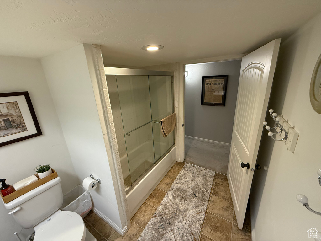 Bathroom with toilet and bath / shower combo with glass door